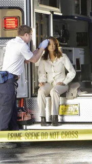 Ein Sanitäter (l. Darst. unbekannt) kümmert sich um Natalia (Eva LaRue), die bei der Untersuchung eines Tatorts nur knapp einer Explosion entkommen konnte.