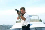 Jan (Nick Wilder) versucht die Verbrecher in ihrem Speedboot mit einem großkalibrigen Gewehr zu stoppen.