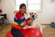 Mit dem stürmischen Therapiehund "Anton" macht Anna Übungen für das Gleichgewicht.