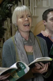Joyce Barnaby (Jane Wymark), Toms Ehefrau, singt in einem Chor.
