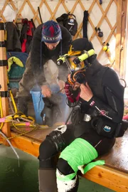 Emily Riedel prepares to go into the dive hole as Steve Riedel inspects gear.