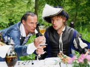 Der Lampenmann (Christian Tramitz, links) zeigt dem Soldaten Jakob (Christoph Letkowski), wie er den Weinkelch richtig halten muss.