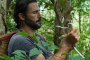 Hazen hält eine Orientalische Peitschenschlange [weiße Morphe] im Dschungel. (National Geographic/Barbara Brunner)