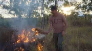 Ein Mann steht an einem offenen Feuer in der Natur