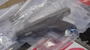 Eine Schusswaffe liegt in einer Plastiktüte auf einem Inspektionstisch, nachdem sie unangemeldet in der Mittelkonsole des Fahrzeugs eines Verdächtigen gefunden wurde. (National Geographic für Disney)