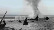 Soldaten am Strand verteidigen sich mit ihren Gewehren gegen ankommende Bomben. (ALAMY)