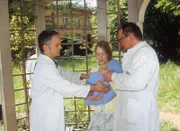 Das Kind, das Elsa Brandt (Anne Kanis) auf dem Arm trägt, hat offensichtlich Angst vor Dr. Friedrich (Rene Hofschneider, l.). (re. Komparse)