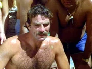 Magnum (Tom Selleck) muss tatenlos zusehen, wie ein Mitbewerber nach einem Kanu-Trainingsrennen am Strand zusammenbricht.