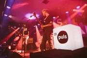Die Band "Endlich Rudern" während ihres Auftritts auf der Bühne "Ballroom" beim PULS Festival 2019 im Funkhaus des Bayerischen Rundfunks in München. Im Vordergrund ist ein Leuchtwürfel mit dem Puls Logo zu sehen.