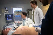 Dr. Jan Kühnert (Marc Dumitru, l.), Dr. Sebastian Sander (Oliver Franck, r.) führen eine Ultraschalluntersuchung bei Ralle (Stephan Fürstenberg, liegend) durch.