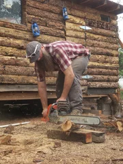 Matt mit der Kettensäge beim Schneiden eines Holzbalkens