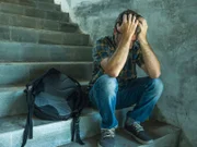 anti sexual discrimination and against homophobia campaign. Young sad and depressed college student man sitting on staircase desperate victim of harassment suffering bullying and abuse