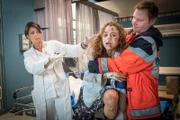 Dr. Haase (Fabian Harloff, r.) und Dr. Jonas (Gerit Kling, l.) versuchen, ihre neue Patientin (Amelie Herres, M.) zu beruhigen, die bei der Einlieferung einen Anfall erleidet.