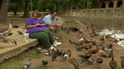 Zsalynn and her husband feeding ducks near a pond.