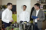 Nils (Martin Baden, li.) gerät bei der Kochprüfung bei Prüfer Weber (Carl Weinknecht, re.) unter Druck. Mi. Koch Richie (Marco Sprinz)