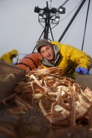 Deckhand Nick McGlashan pushes crab down the chute and into the Cape Caution's crab tanks.