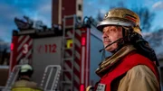 Ein Feuerwehrmann der Feuer- und Rettungswache 3 in Duisburg steht vor einem Hilfeleistungslöschgruppenfahrzeug (HLF).