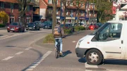 Ein Fahrradfahrer fährt knapp vor einem Transporter über die Straße.