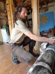 MARS HILL, N.C.- Tony putting bricks in place on their indoor heating system. (Photo Credit: NG Studios/Caitlin Grossjung)