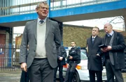 DCI Colin Sutton (Martin Clunes) und einige Kollegen auf dem Parkplatz vor dem Revier. Sutton versucht sein Team für den anstehenden Überwachungseinsatz zu motivieren.