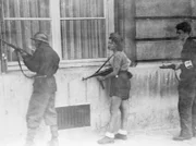 (Originalbildunterschrift) 28.8.1944-Paris, Frankreich: Diese junge Französin in ihrer Einsatzkleidung hält sich dicht an einer Mauer und hält ihre Maschinenpistole bereit, um im Handumdrehen zu schießen. Sie gehört zu einer Patrouille, die deutsche Scharfschützen aufspüren soll, die sich noch in Paris verstecken.