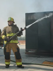 Tory und Tommy posieren mit einem Mitglied der RCFD und einem Feuerwehrschlauch