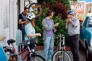 Mike (Harry Blank, links) gibt Till (Marinus Hohmann, Mitte) eine zweite Chance in seiner Fahrradwerkstatt. Mit Komparserie (2. von links, rechts).