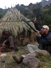 Feuer brennt, während Josh James (l.) Grady Powell (r.) beim Trinken aus dem Reifen zusieht.