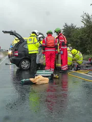 Feuerwehr und YAA-Crew arbeiten auf nasser Straße.