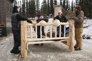 The Deeters and the Raneys standing around the wooden bed which the Raneys created as a present to the Deeters.