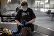 CBP-Beamter Axson untersucht die Brieftasche eines Passagiers während einer Gepäckkontrolle in Atlanta, Ga. (National Geographic for Disney)