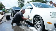 Dan McKernan washes down cars at a cow brush fundraiser for Barn Sanctuary.