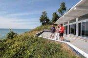 Real estate agent Ronda Busscher shows off the 75-feet of waterfront at the Cali Beach House to homebuyers Darren and Cindy.