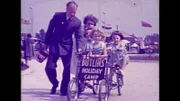 Mann, Frau und drei Kindern, die einen Wagen schieben auf dem steht "BUTLINS HOLIDAY CAMP".