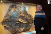 Joe Bonsor steht neben einer Matrix aus Iguanadontid-Fossilien.