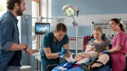 Mikko Rantala (Luan Gummich, 2.v.l.) und Viktoria Stadler (Isabella Krieger, r.) lernen in der Notaufnahme die schwangere Lena Wegner (Luisa-Celine Gaffron, 2.v.r.) kennen. Lena hat sich den Fuß so ungünstig verletzt, dass dieser nun dringend operiert werden muss. Ihr Mann Robin Wegner (Wolf Danny Homann, l.) eilt zu ihr.