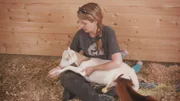 Alicia stretching out goat rescue Lola’s legs.