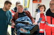 Ein rostiger Nagel hat sich durch Gilbert Keils (Christoph Glaubacker, M.) Schuhsohle gebohrt. Mikko Rantala (Luan Gummich, l.) und Karin Patzelt (Marijam Agischewa, 2.v.r. mit Komparsen) nehmen den Patienten in der Notaufnahme an.