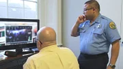 Ein Detektiv und ein Polizeibeamter sehen sich Sicherheitsvideos an.