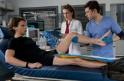 Elly Winter (Juliane Fisch, M.) und Florian Osterwald (Lion Wasczyk, r.) untersuchen das Knie von Daniel Harder (Luis Pintsch),