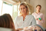 Lena Lorenz (Judith Hoersch, M.), aufmerksam beobachtet von Praktikantin Celine Gollert (Paulina Rümmelein, r.), hat den Verdacht, dass die körperlichen Symptome von Tati Meisinger (Anouk Elias, l.) auf psychischen Ursachen beruhen.