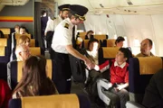 Kapitän Garanito Gomez (gespielt von Alex Karzis) und der Erste Offizier Ferreira Quintal (gespielt von Rodrigo Fernandez-Stoll) halten an, um den Passagier Eisberth Quintero (gespielt von Isaac Pilozo) auf ihrem Weg zum Cockpit des Santa Barbara Airlines Fluges 518 zu begrüßen. Die Piloten sind mit Verspätung eingetroffen und gehen als letzte an Bord des Flugzeugs. Foto: Cineflix/Ian Watson