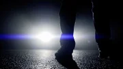 Eine Person steht in der Dunkelheit