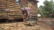 Matt mit der Kettensäge beim Schneiden eines Holzbalkens