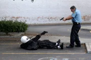 The policeman aimed his gun at the wounded perpetrator.