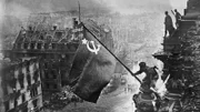 Soldaten hissen die sowjetische Flagge auf dem Reichstag über dem zerbombten Berlin. Ein ikonisches Bild vom Ende des Zweiten Weltkriegs.