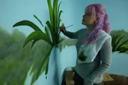 Carrie Fuchs paints a background in the Blue Iguana exhibit.