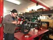 Workshop - mechanic fixing the damaged bulb headlight on the motorbike.