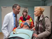 Als Prof. Simoni (Dieter Bellmann, liegend) von der Notärztin (Komparsin) und Oberschwester Ingrid (Jutta Kammann, rechts) in die Sachsenklinik eingeliefert wird, wartet Dr. Roland Heilmann (Thomas Rühmann) schon auf sie.