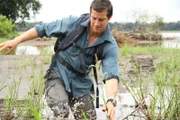 Bear Grylls wades through river in Zambia.